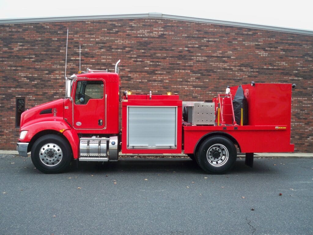 A red truck parked in front of a brick wall.