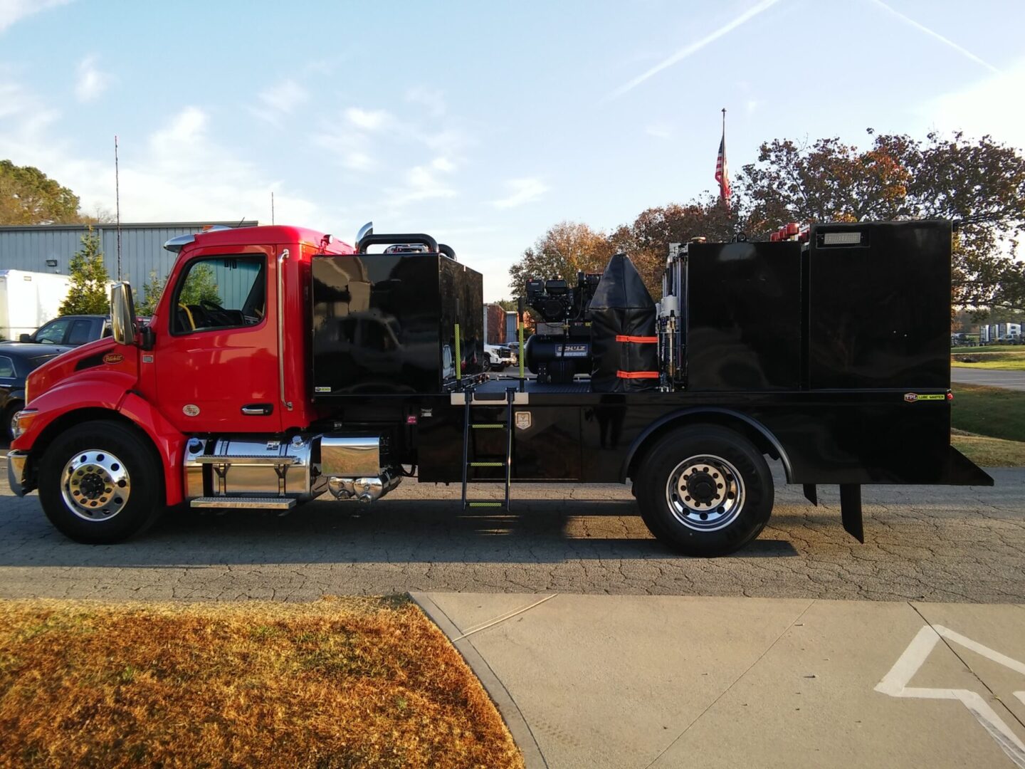 A red truck with a black trailer parked on the side of the road.