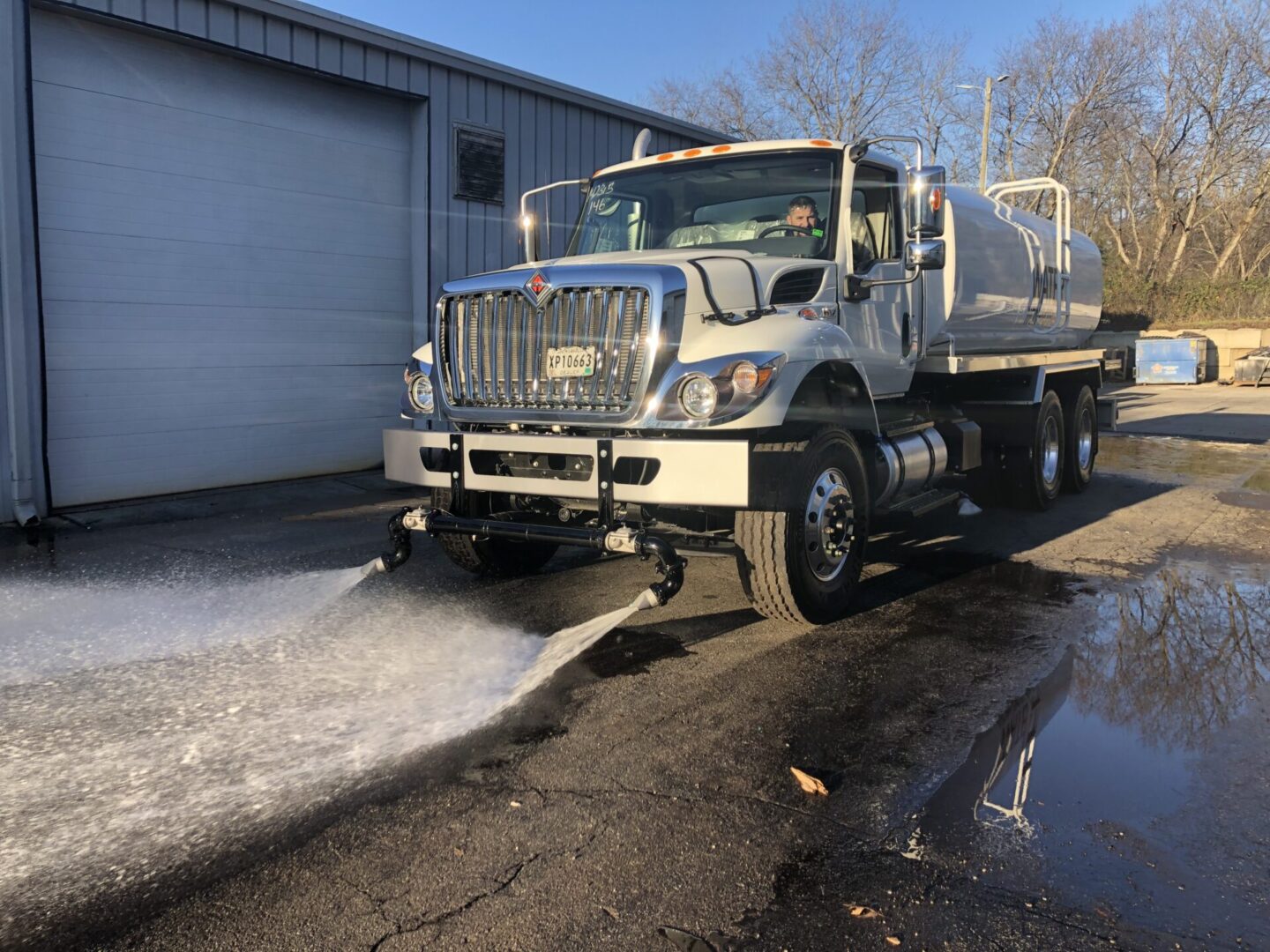 A truck is spraying water on the street.