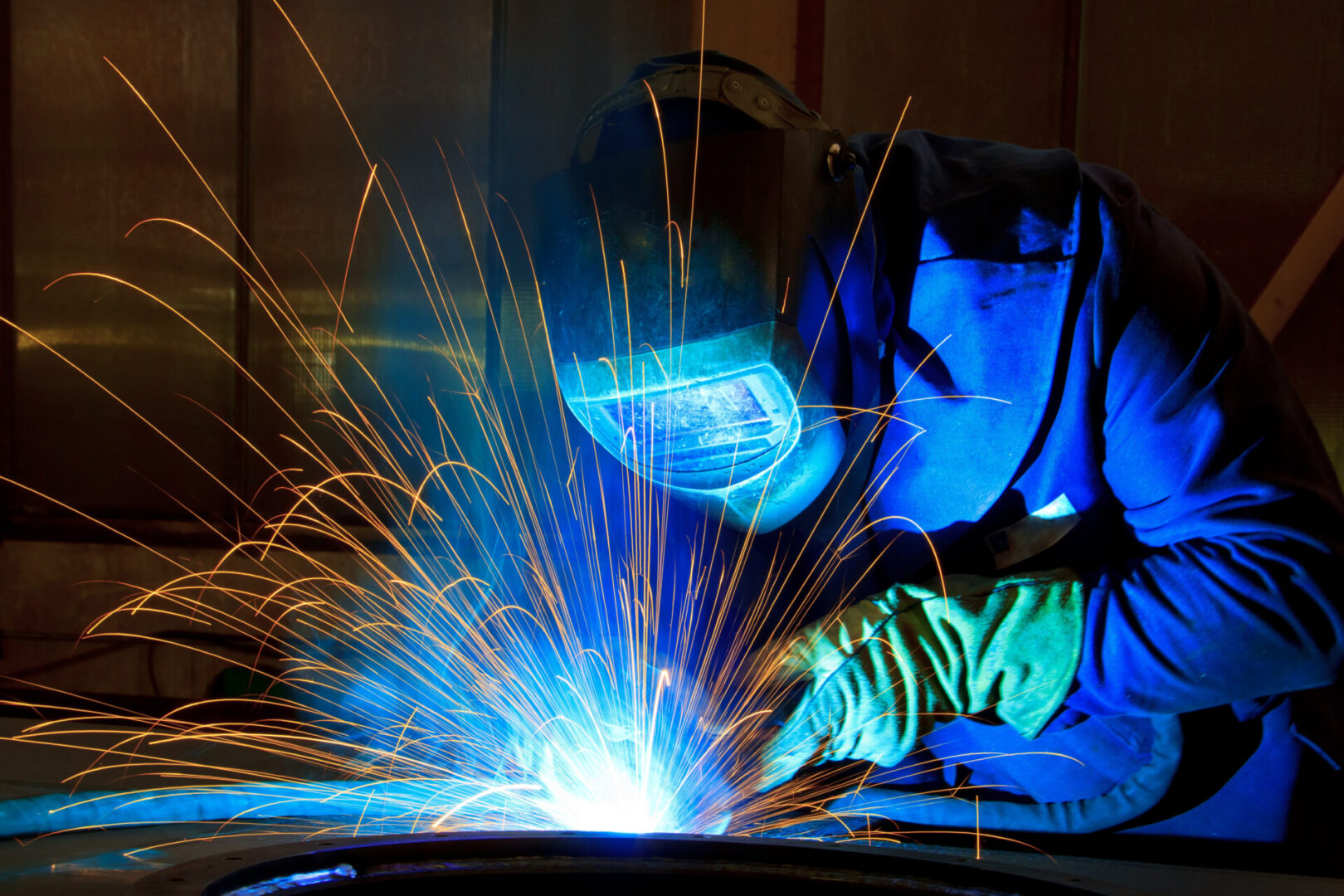 A person welding with blue light shining on them.