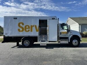 Service truck with open rear door parked on a suburban street.
