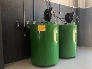 Bulk oil storage tanks with hose reels in a fleet shop fluid management system for faster lubricant dispensing and cleaner waste oil handling.