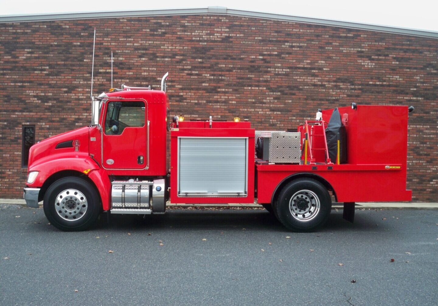 A red truck parked in front of a brick wall.