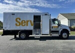 Service truck with open rear door parked on a suburban street.