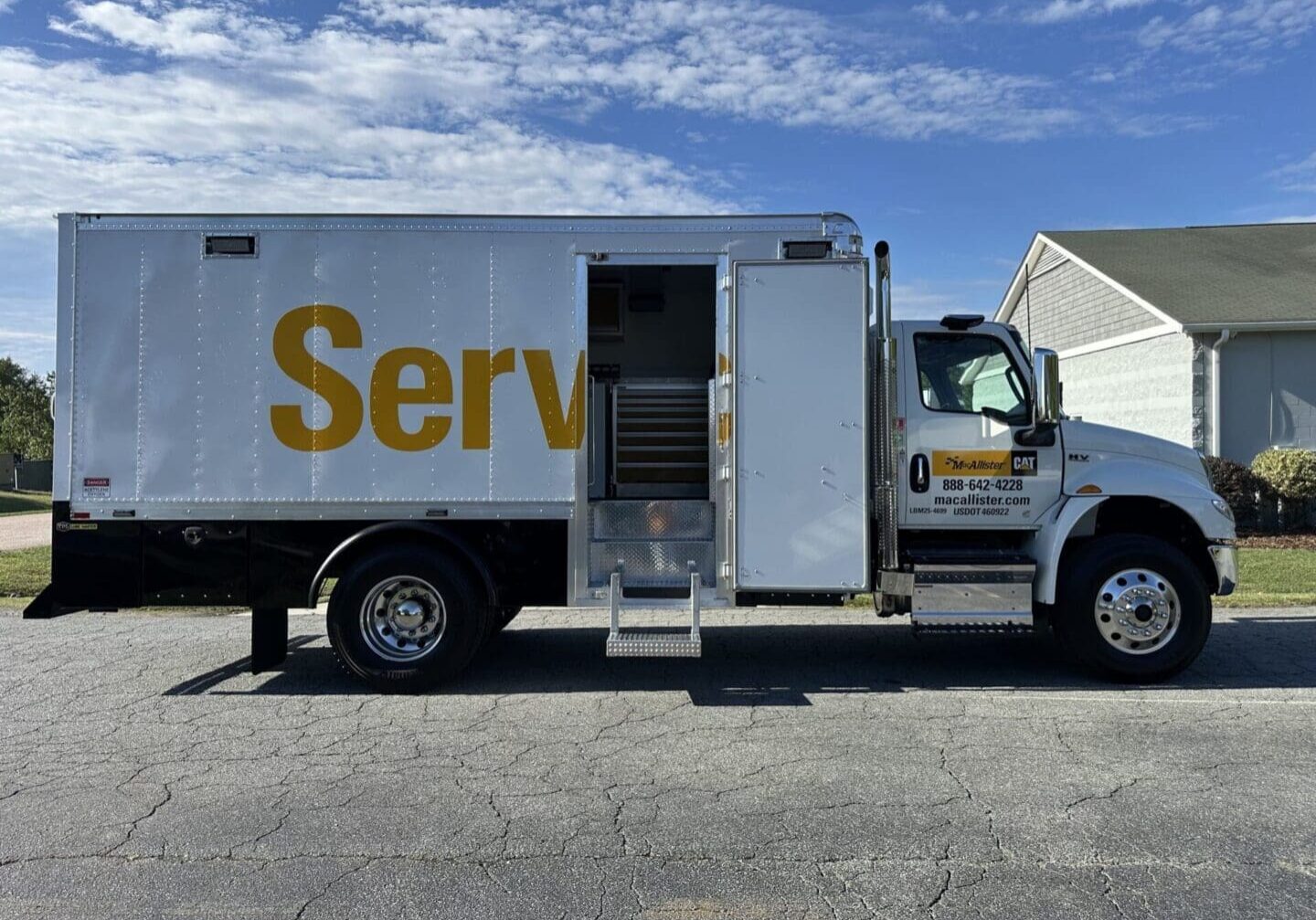 Service truck with open rear door parked on a suburban street.